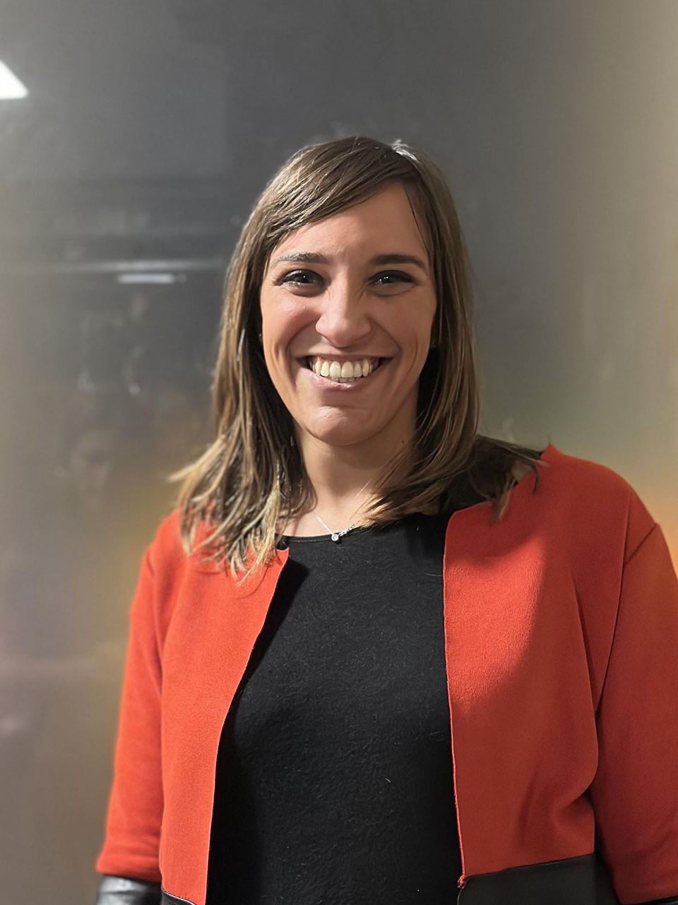 Ritratto: una ragazza sorridente con un cardigan arancione.