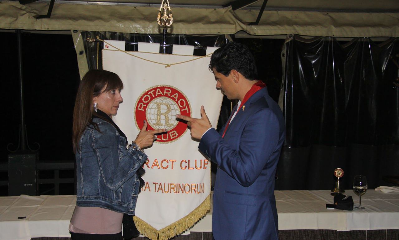 Foto d’archivio: un ragazzo e una ragazza si scambiano un gesto scherzoso davanti a uno stendardo Rotaract.