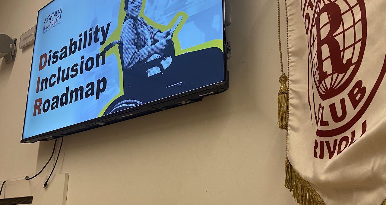 Lo schermo con la presentazione «Disability Inclusion Roadmap» dell’Agenda della Disabilità, accanto allo stendardo del club.