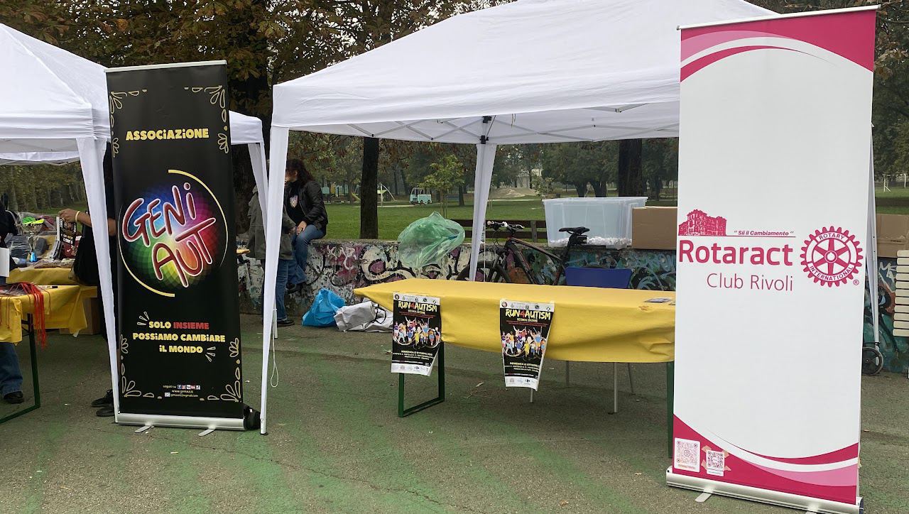 Il gazebo con il roll-up del Rotaract Club Rivoli e lo stendardo dell’associazione Geniaut, in un parco.