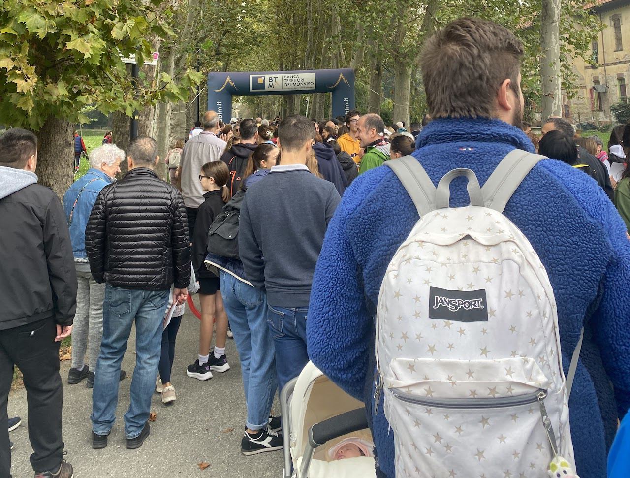I partecipanti in un viale alberato, visti di spalle, verso l’arco della partenza.