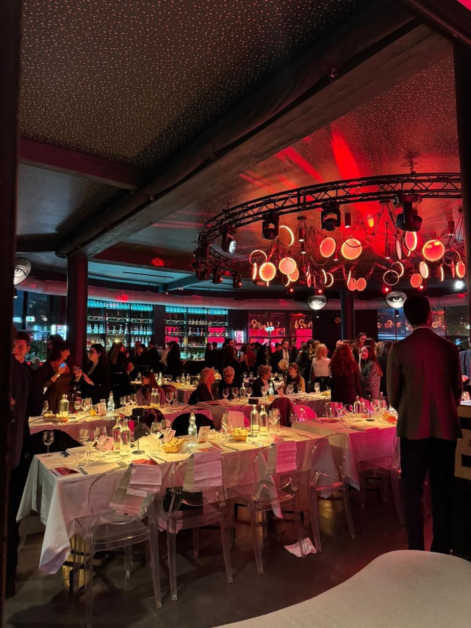 La sala della cena, con i tavoli apparecchiati sotto le luci rosse.