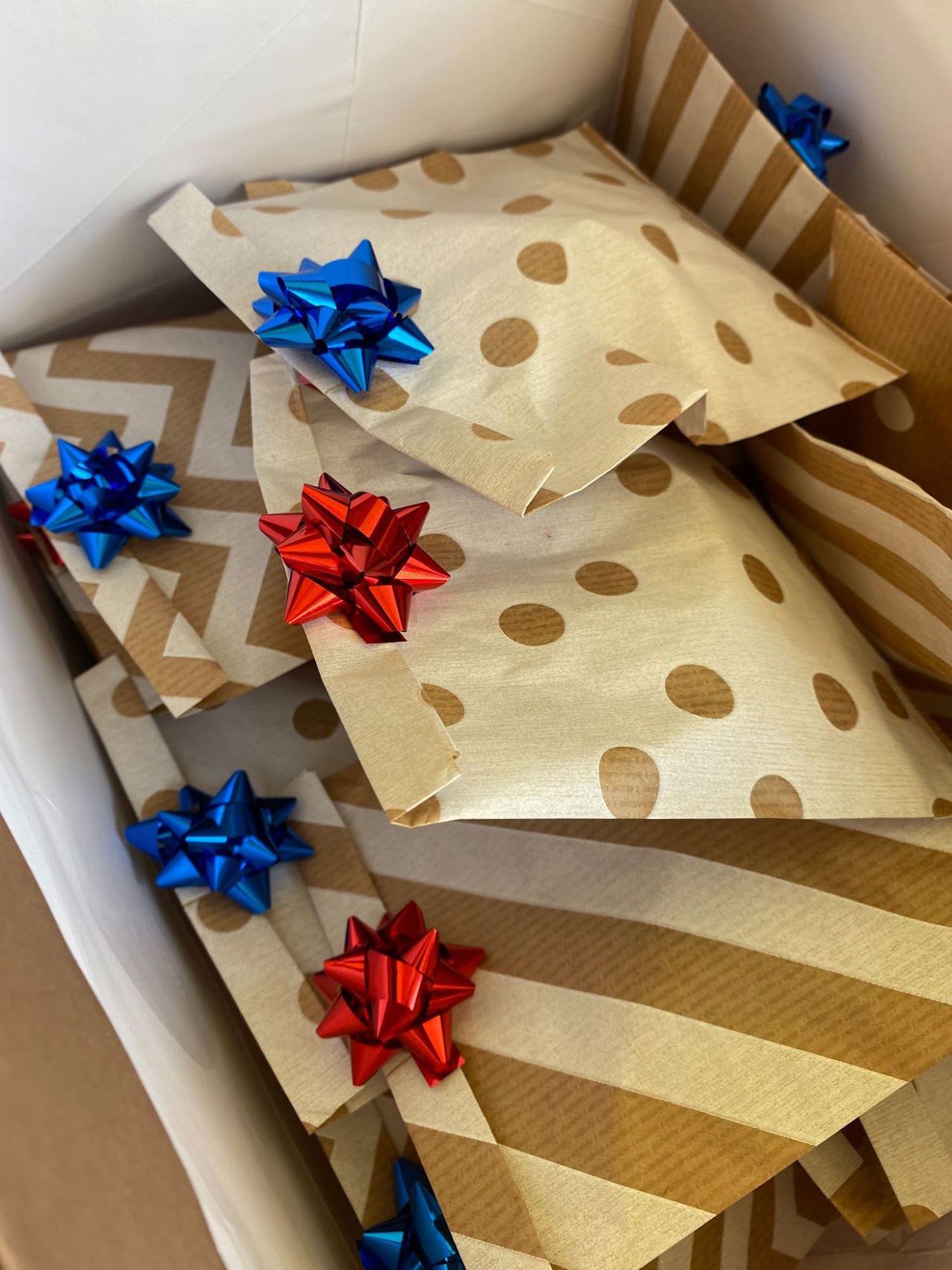Pacchetti regalo con fiocchi rossi e blu dentro una scatola.