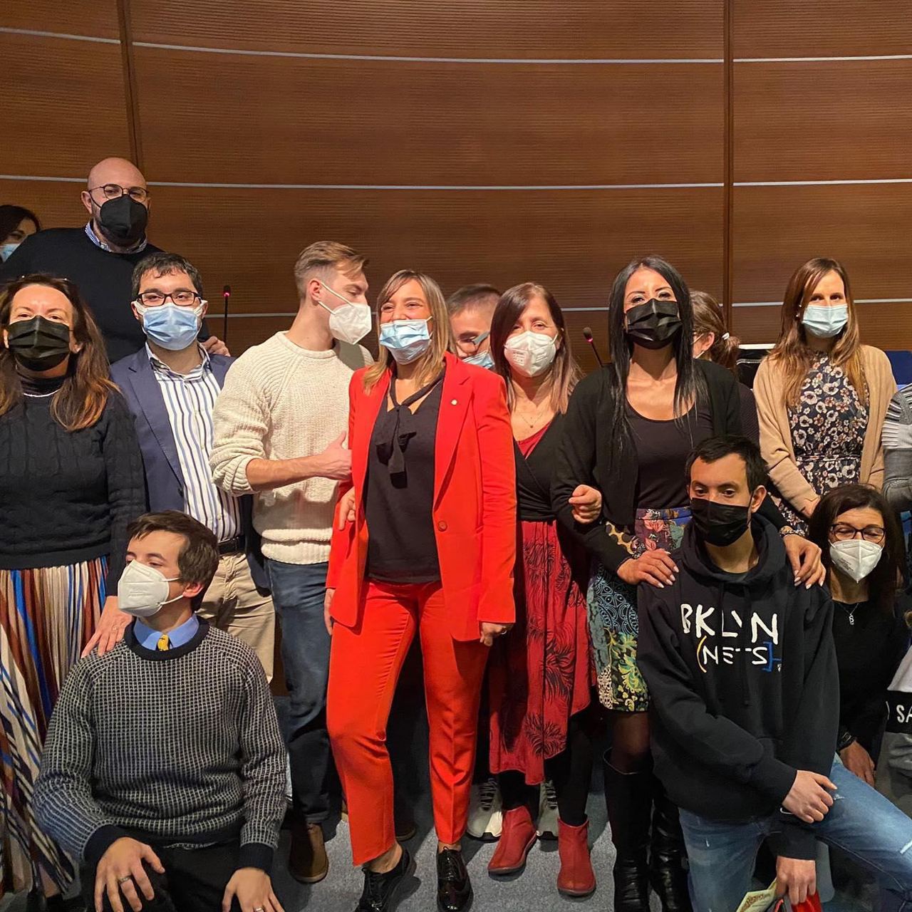 Foto di gruppo di studenti e accompagnatori, con la mascherina, in un auditorium.